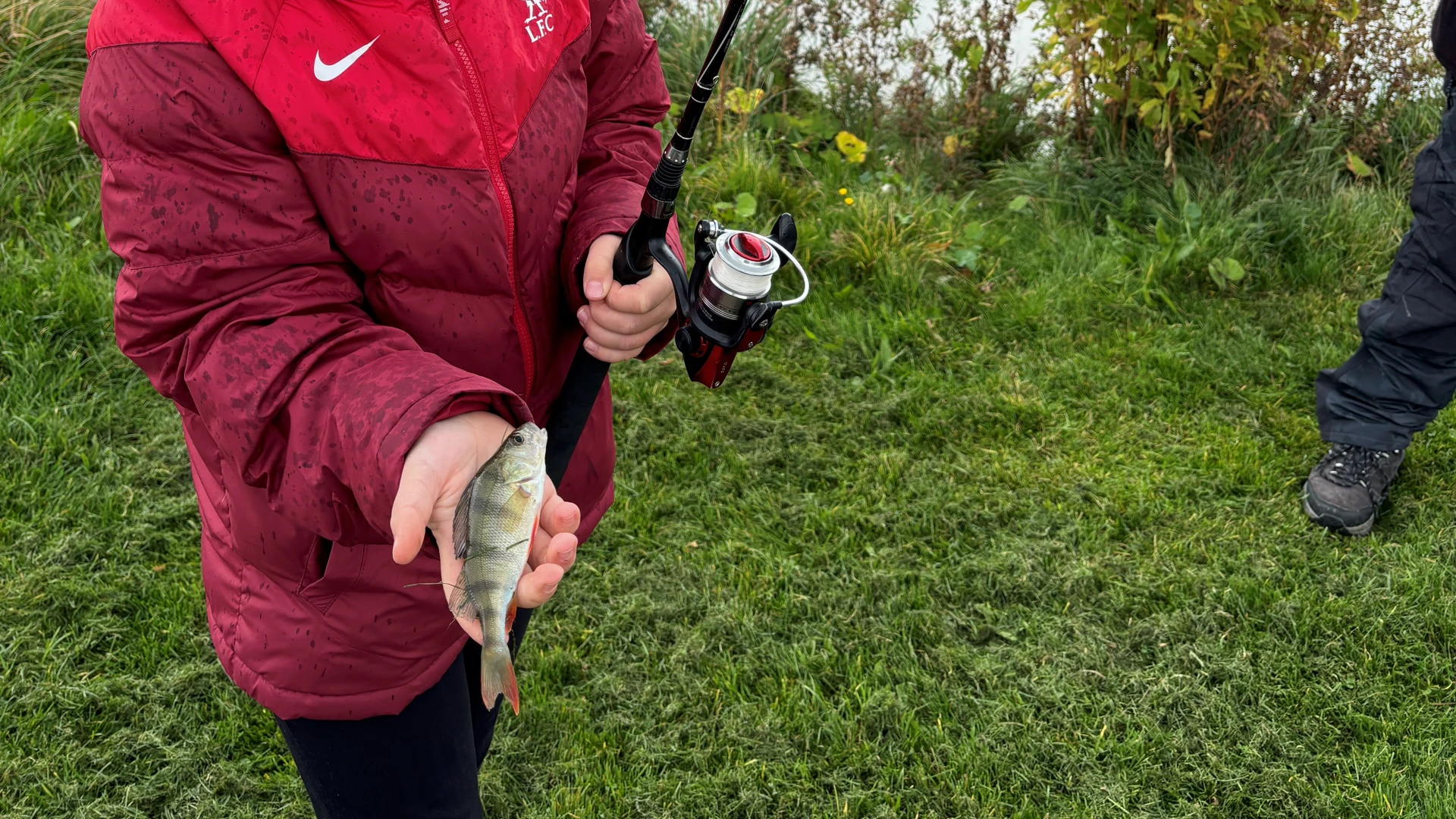 Barn med fiskestang og en fisk i hånden