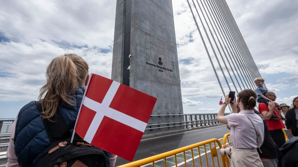 Billede af mennesker samlet med flag foran pylonen på en bro