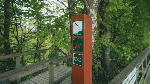 Billede af en stolpe med forskellige skilte på trapperne ved Møns Klint