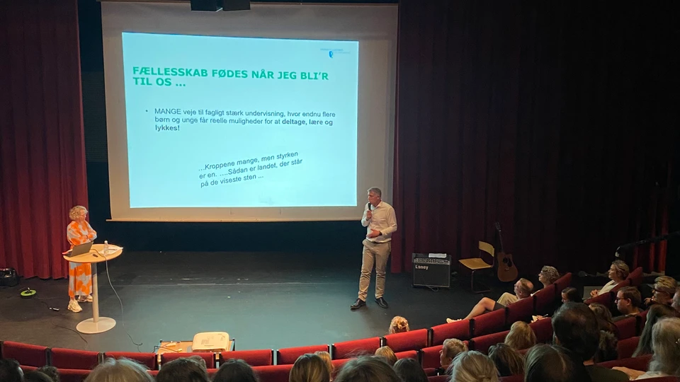 Billede af to mennesker på en scene, der laver en præsentation for publikum