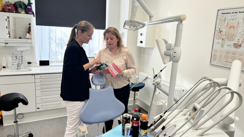To mennesker i en tandlægeklinik kigger på indholdet i en energidrik